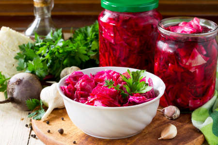 Homemade preserving. Fermented food. Salad Cabbage with Beetroot on the kitchen wooden background.の写真素材