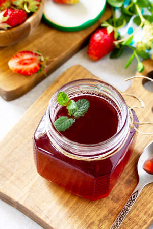 Homemade preservation. Fresh strawberry berries and strawberry berry syrup on a light stone table.の写真素材
