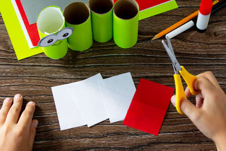Child cuts out details Paper Roll Pencil Holder the new school year. Welcome back to school. Children's Art Project, needlework, crafts for kids.の写真素材