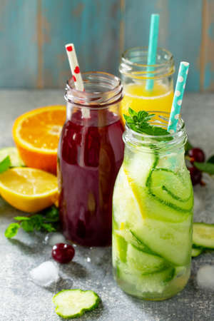 Various refreshments drinks - detox cucumber water, cherry juice and orange juice on stone table.の写真素材