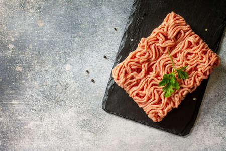 Fresh Raw mince. Ground Minced beef on stone slate blackboard. Top view flat lay with copy space for...