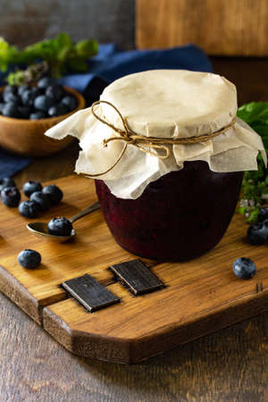 Homemade Preserves. Organic Blueberry jam in a jar and fresh blueberries on rustic wooden table....