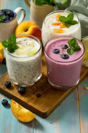 Healthy Chia set. Pudding in a glass with blueberry, with melon and peach on wooden kitchen table. Healthy breakfast, vitamin snack, diet and healthy eating. Space for  text.の写真素材