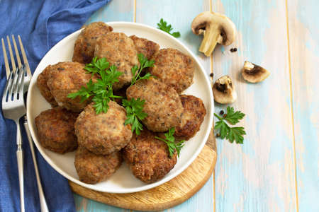 Homemade meatballs with mushrooms on the kitchen wooden table. Copy space.の写真素材