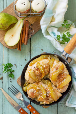 Thanksgiving menu. Baked turkey fillet with caramelized pears in a pan on the kitchen table. Top view on a flat background lay.の写真素材