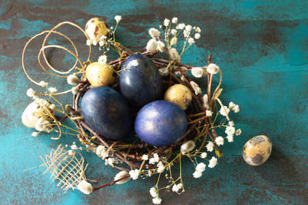 Blue easter eggs in a nest on a blue stone or slate background. 