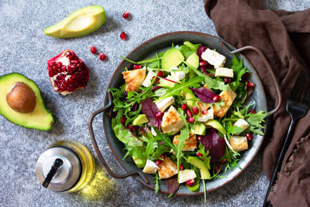 Salad with grilled chicken, avocado, brie cheese, arugula and pomegranate with vinaigrette dressing....