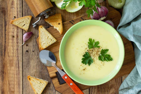 The concept of healthy and diet food, vegetarian dish. Delicious vegetable soup with cream and zucchini on a rustic table. Top view flat lay background. Copy space.の写真素材