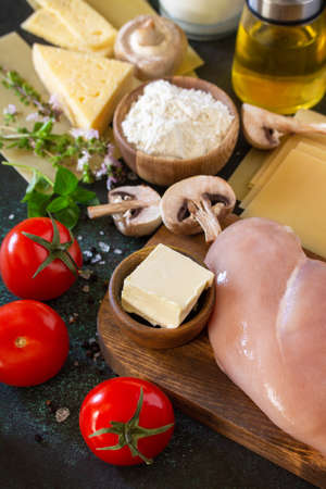Food background italian. Ingredients for cooking lasagna with chicken and mushrooms on a dark stone background.の写真素材