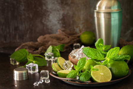 Refreshing Mojito cocktail making. Mint, lime, ice ingredients and bar utensils on a dark stone background. Copy space.の写真素材