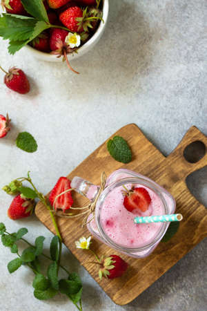 Natural detox, fruit dessert, healthy dieting concept. Strawberry fruit Yogurt smoothie or milk shake in glass jar on a light stone or slate table. Top view flat lay background. Copy space.の写真素材