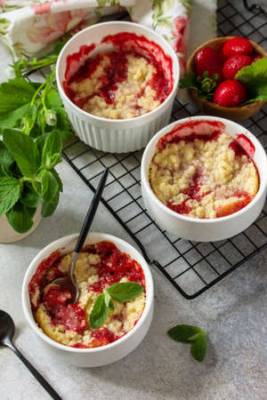 Homemade summer dessert. Strawberries crumble in baking dish on a tabletop made of stone or slate.の写真素材