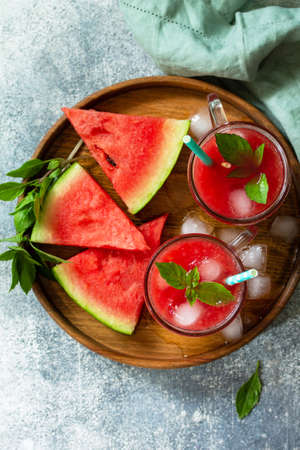 Cold Watermelon Smoothie. Summer Watermelon drink and slices of watermelon on a light stone table....