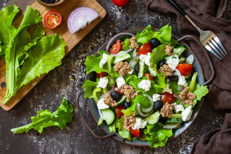 Healthy summer lunch. Greek salad with canned tuna, vegetables and lettuce on a stone countertop.の写真素材