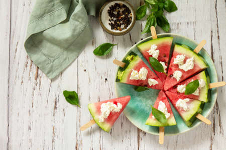 Healthy dieting and nutrition, seasonal snack. Watermelon pizza with feta cheese and basil on a wooden table. Top view flat lay background. Copy space.の写真素材
