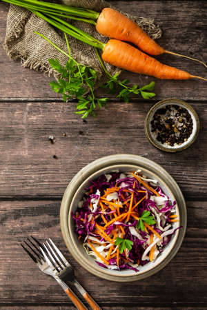 Salad Cole Slaw. Autumn Cabbage salad in a bowl on a rustic wooden table. Flat lay top view. Copy space.の写真素材