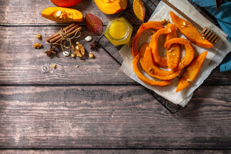 Pumpkin dessert. Baked pumpkin slices with honey, cinnamon and walnuts on a rustic table. Top view flat lay background. Copy space.の写真素材
