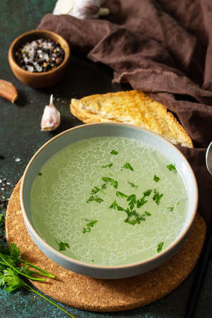Healthy lunch. Hot rich meat broth (bouillon) with herbs and garlic croutons on a dark slate...