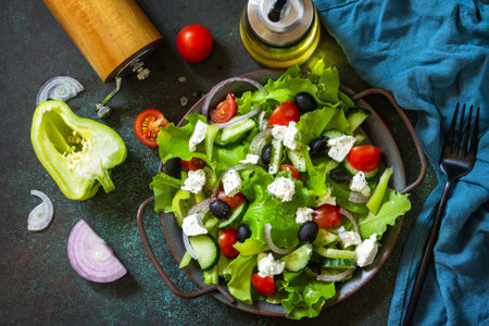 Healthy diet food. Greek salad of feta cheese, fresh cucumber, tomato, sweet pepper, lettuce, red onion and olives with olive oil. Top view flat lay.の写真素材