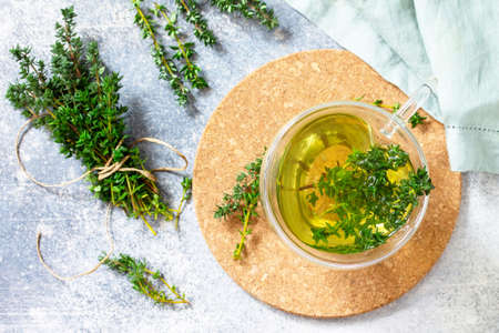 Therapeutic herbal tea. Hot cup of thyme tea on a light stone countertop. Top view flat lay.の写真素材