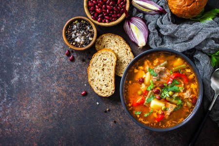Homemade Meat Tomato soup with beef and bean stew, vegetables on a stone tabletop. Top view flat...