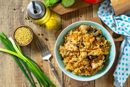 Bulgur with turkey and prunes is served with fresh vegetable on a rustic table. Top view flat lay.の写真素材