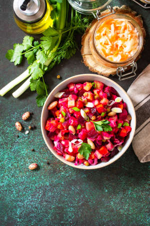 Beetroot salad vinaigrette with pickled cucumber, beans, carrots, peas, sauerkraut on a dark countertop. Top view flat lay. Copy space.の写真素材