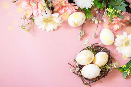Easter floral background. Spring flowers gerbera with easter eggs on pink background. Top view flat lay. Copy space.の写真素材