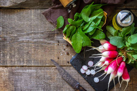 Summer salad ingredients, organic vegetables and olive oil. Raw fresh juicy radish on a rustic...
