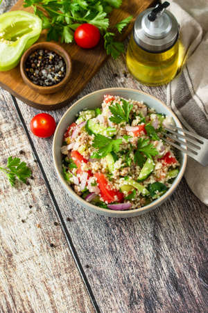 Food dieting concept, tuna salad. Couscous salad with conserved tuna, tomatoes, cucumbers and purple onions on rustic wooden table. Copy space.の写真素材