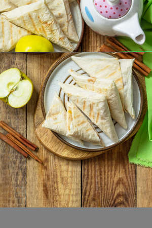 Apple pastries for breakfast. Grilled lavash triangle with apples and cinnamon on a wooden wooden...