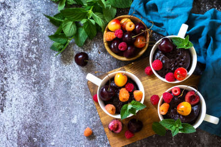 Summer breakfast or dessert. Chocolate cupcake in a mug is served with fresh summer berry raspberries and cherries. Top view flat lay background. Copy space.の写真素材
