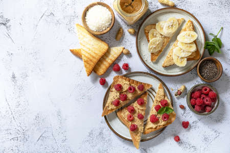 Sweet dessert sandwich breakfast. Tasty toasted with peanut butter, banana and raspberry on a gray stone table top. Top view flat lay background. Copy space.の写真素材