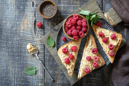 Summer sweet dessert sandwich breakfast. Tasty toasted with peanut butter and raspberry on a rustic wooden table. Top view flat lay background. Copy space.の写真素材