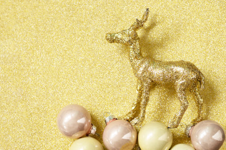 Magic of christmas. Christmas deer gold color palette with decor on a gold background for your greeting card. Top view flat lay. Copy space.の写真素材