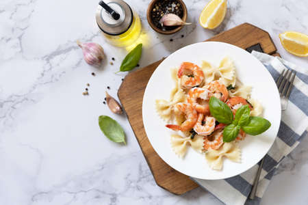Mediterranean cuisine, seafood diet. Italian farfalle pasta with prawns garlic, basil and lemon on a marble tabletop. Top view flat lay. Copy space.の写真素材
