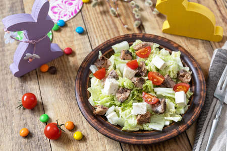 Holiday food, easter salad. Salad with chinese cabbage, feta, cherry and tomatoes canned tuna and vinegar dressing on a festive table.の写真素材