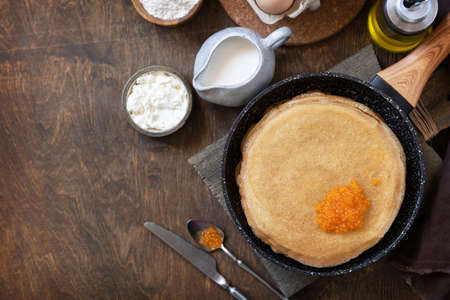 Pancakes traditional Russian cuisine. Thin lacy pancakes served with red caviar on a wooden table....
