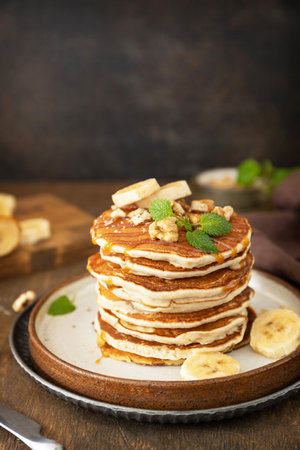 Celebrating pancake day, american breakfast. Delicious homemade banana pancakes with nuts and caramel on rustic wooden table. copyspace.の写真素材