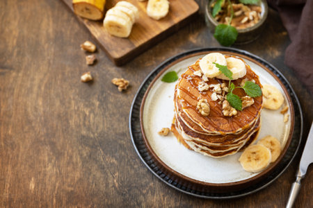 Celebrating pancake day, american breakfast. Delicious homemade banana pancakes with nuts and caramel on rustic wooden table. copyspace.の写真素材