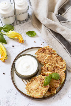 Zucchini fritters. Vegetarian zucchini pancakes with cheese, served with sour cream on a rustic wooden table. Healthy food, low calories keto dieting meal.の写真素材