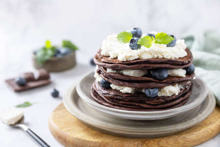 Celebrating pancake day. Delicious homemade american bananas chocolate pancakes with blueberries and ricotta on on a marble tabletop.の写真素材