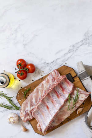 Raw veal calf brisket ribs meat with vegetable and spices on short spare rib for cooking on marble...