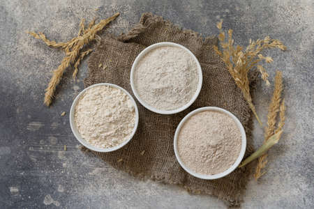 Food and baking ingredient. Wheat flour coarse from whole wheat grains, wheat bran and wheat flour over gray stone background. Top view flat lay.の写真素材