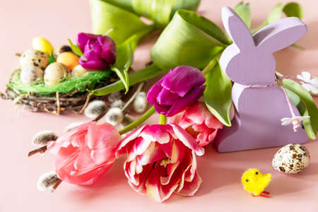 Pink and purple tulips with colorful quail eggs in a nest over pink background. Spring and Easter holiday concept.の写真素材