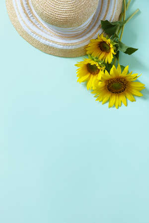 Straw hat and sunflowers on pastel green background. Summer holiday, vacation concept. Flat lay, top view, copy space.の写真素材