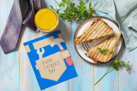 Celebrating Father's Day. breakfast. Father's Day card and home DIY sandwich with bacon on wooden table. view from above.