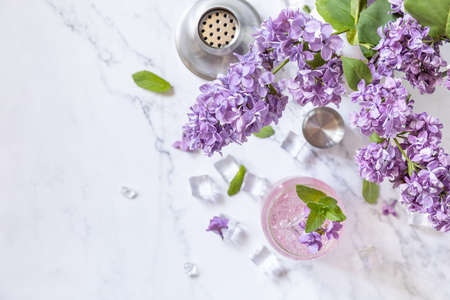 Lilac drink, infused drink from lilac flowers. Organic natural daikiri cocktail or mocktail, lilac lemonade with ice on a marble table. view from above. copyspace.の写真素材