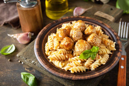 Italian homemade kitchen. Italian fusilli pasta gluten free with meat balls in tomato sauce and basil on rustic table.の写真素材