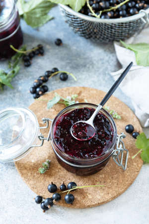 Summer seasonal berry jams, homemade preservation concept. Blackcurrant jam, marmalades or confitures with fresh berries on a stone tabletop.の写真素材